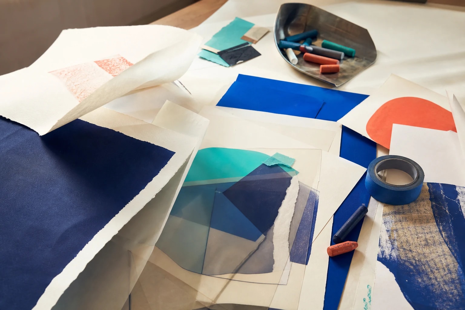 Mesa de processo criativo com papéis, acetatos, tintas e estudos visuais nas cores da TÊ Comunicação